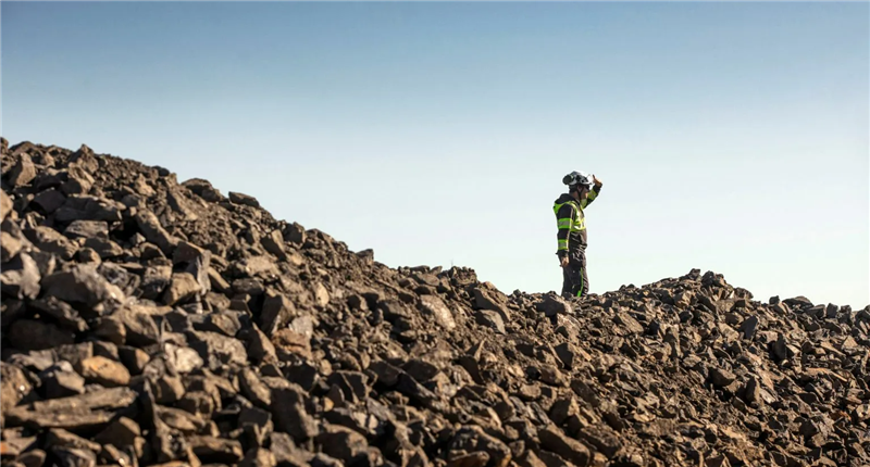 A Talga Group worker stands on a graphite pile in Sweden.
