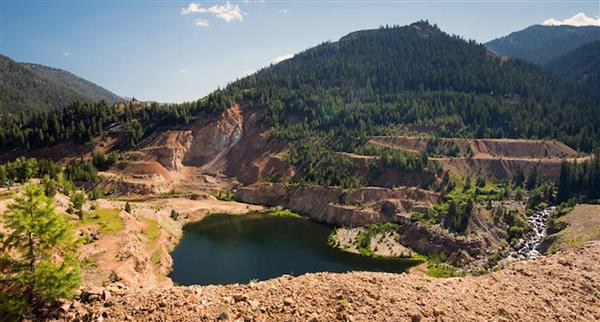 A large creek surrounded by rocks and mountains in the Stibnite District in Idaho.