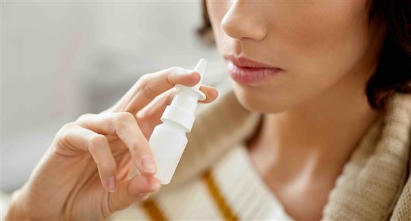 A consumer uses a generic bottle of nasal spray.