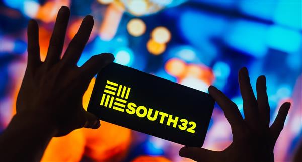 Image of a person holding a phone with the South32 logo