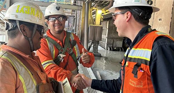 Three Capstone Copper Corp workers shake hands and put thumbs up in an on-site promotional image.
